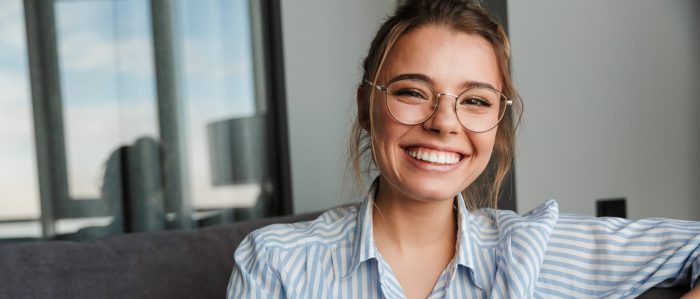 Image Of Happy Young Woman In Eyeglasses Smiling And Using Cellp